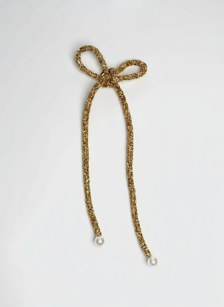 Gold glittery hair tie with a pearl on a white background